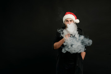 Man with beard in Santa red hat smoking electronic sigarette. vape pen. vape smoke. Christmas concept