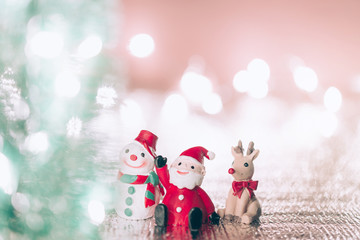 A miniature Santa Claus with his reindeer  and Snowman on Christmas background.Xmas greeting card with copy space.