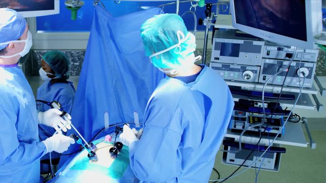 Caucasian and Multi ethnic surgical team in scrubs performing Laparoscopy surgery on the patient in operating theatre using video camera technology 