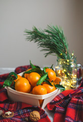 Wooden Basket Mandarine with Leaves and Lights, Tangerine Orange on Gray Table Background Christmas New Year Decors Party Concept