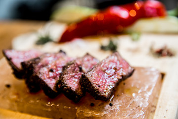 Juicy medium Beef Rib Eye steak slices in pan on Himalayan pink salt plates.