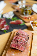Juicy medium Beef Rib Eye steak slices in pan on Himalayan pink salt plates.