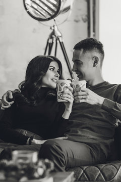 Beautiful couple sitting at romantic atmosphere looking each other, talking, smiling and drinking warm tea. Pregnant wife and her husband spanding time together at kitchen. Pragnancy family concept.