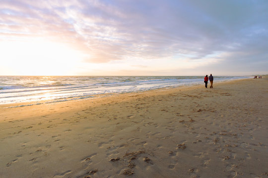 Fototapeta At the seaside, people walking at the beach at the north sea