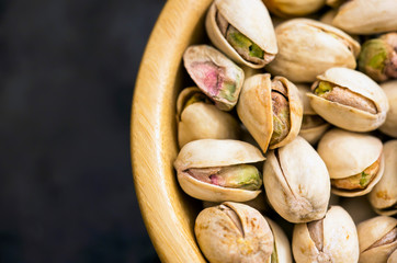 Dried pistachio nuts closeup with shell in bamboo bowl