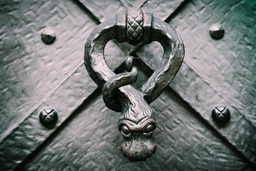 Medieval door handle, macro view. Czech, Prague doorhandle knocker closeup, mystic snake figure.