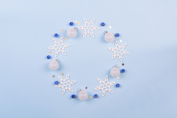 Christmas or winter composition. Snowflake, blue berries and decoration bals wreath on pastel blue background. Christmas, winter, new year concept. Flat lay, top view, copy space