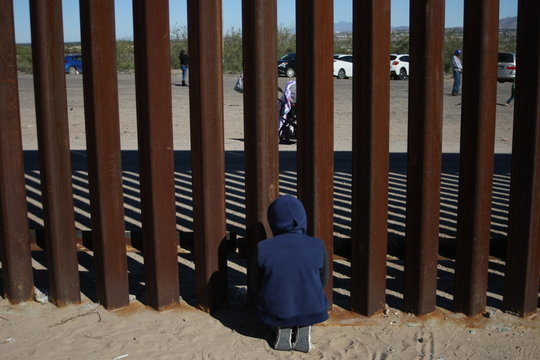 personas se saludan entre el muro que divide mexico de estados unidos