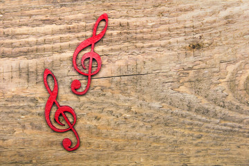 Red wooden treble clef on wooden background, copy space