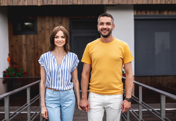 Joyful pair of people in love holding hands and looking at camera with smile. Waist up portrait