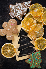 Crispy fruit chips made of orange and gingerbread christmas cookies over dark brown stone surface, above view, vertical shot