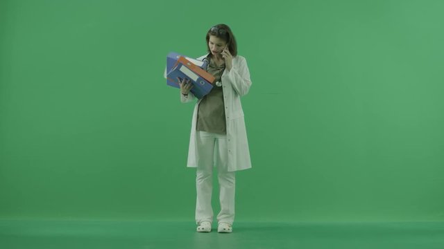 the doctor talks on the phone and holds folders on green screen