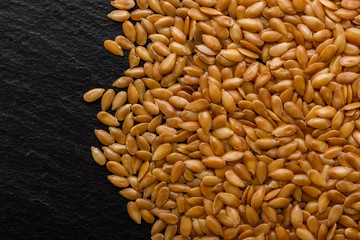seeds of golden flax on a dark stone background
