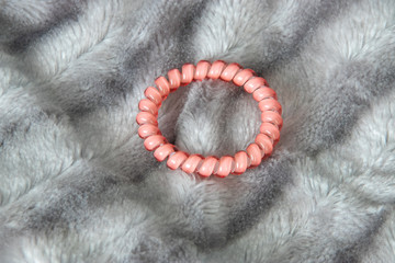 Obraz premium One pink scrunchy hair tie elastic spring on the silver gray fluffy faux fur blanket background