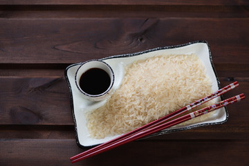Uncooked steamed thai rice on a white plate, elevated view on a rustic wooden background, horizontal shot