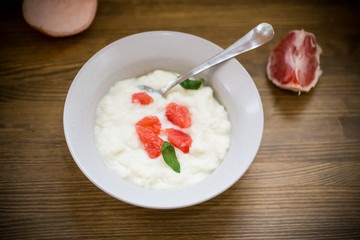 sweet boiled semolina porridge in a plate with slices of red grapefruit