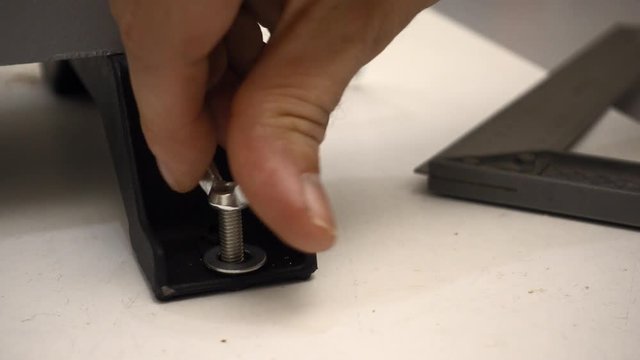 DIY - Man tightening screw with wingnut and washer on machine in the workshop