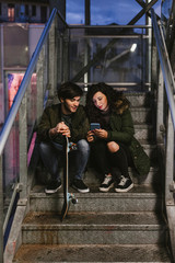 Obraz na płótnie Canvas Couple of teenagers look at the smartphone on an outdoors staircase