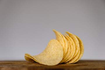 Bunch of salty crisps presented on a wooden board, grey background