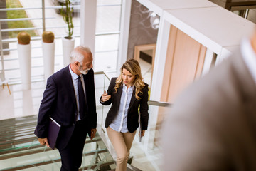 Businessman and businesswoman walking and taking stairs in an office building
