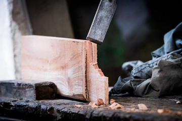 Hands of carpenter with chisel in the hands on the workbench in carpentry