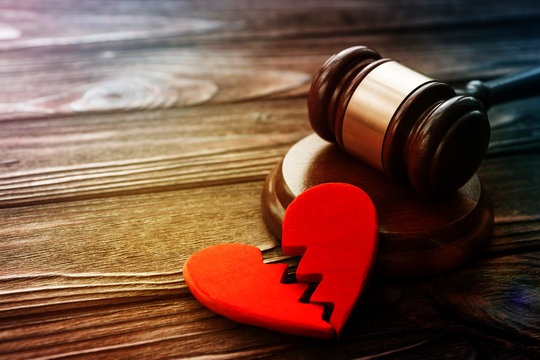 judge's hammer, two halves of heart on wooden background. divorce, conflict, family law.