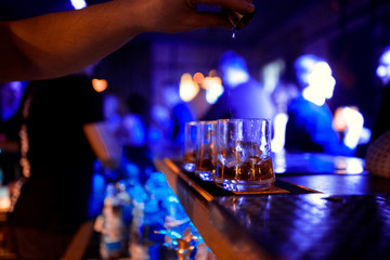 Pink cocktails at the bar. Cocktail set at the night club. Professional  bartender pours alcoholic drink into small glasses on bar. Close up of pink cocktail splash.