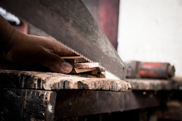 Carpenter working cutting plank with handsaw