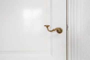 Wooden white door, with gold door handle close-up