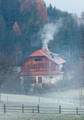 Forest house in the mountains. Smoke comes from the chimney