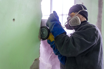 Construction worker cutting concrete wall by using electric cutter.