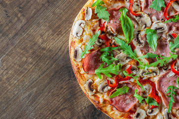 Pizza with Mozzarella cheese, mushrooms, ham, tomato sauce, salami, pepper, Spices and Fresh arugula. Italian pizza on wooden table background