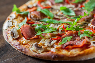 Pizza with Mozzarella cheese, mushrooms, ham, tomato sauce, salami, pepper, Spices and Fresh arugula. Italian pizza on wooden table background