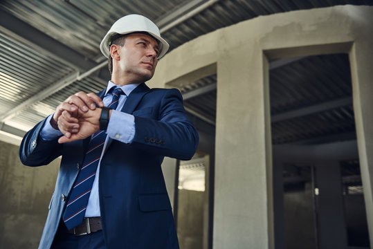 Waist up portrait of adult project manager is standing and checking time while using smartwatch. Copy space on right side