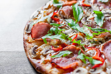 Pizza with Mozzarella cheese, mushrooms, ham, tomato sauce, salami, pepper, Spices and Fresh arugula. Italian pizza on wooden table background