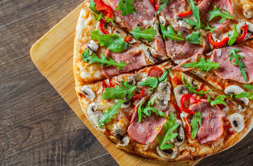 Pizza with Mozzarella cheese, mushrooms, ham, tomato sauce, salami, pepper, Spices and Fresh arugula. Italian pizza on wooden table background