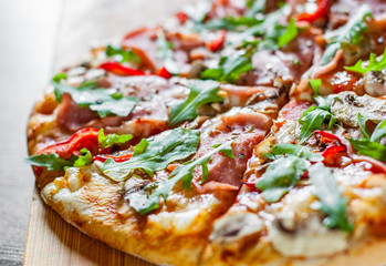 Pizza with Mozzarella cheese, mushrooms, ham, tomato sauce, salami, pepper, Spices and Fresh arugula. Italian pizza on wooden table background