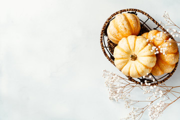 Top view on a decorative small pumpkins in a basket on a white background. Winter colors,  flat lay, place for text.