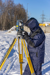 A surveyor enters the survey data for a cadastre at a construction site during the winter period.
