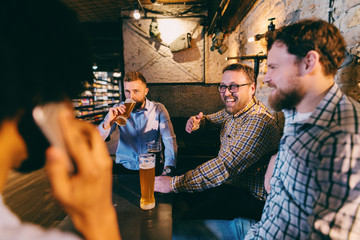 Happy friends sitting and talking in pub.