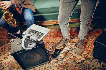 Musicians having rehearsal in home studio. On the floor amplifiers, laptop and headphones.