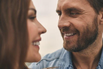 Close up of happy man is tenderly looking at pretty smiling woman while standing outdoor