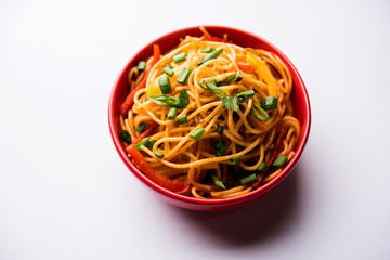 Schezwan Noodles or vegetable Hakka Noodles or chow mein is a popular Indo-Chinese recipes, served in a bowl or plate with wooden chopsticks. selective focus