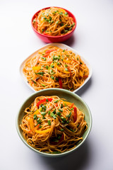 Schezwan Noodles or vegetable Hakka Noodles or chow mein is a popular Indo-Chinese recipes, served in a bowl or plate with wooden chopsticks. selective focus