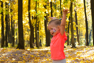 Little happy girl playing in autumn park