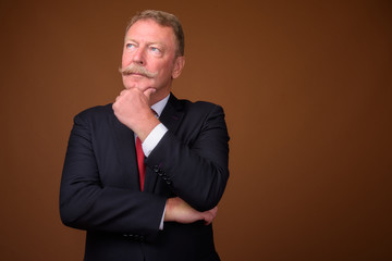 Senior businessman wearing suit and tie while thinking and looking up