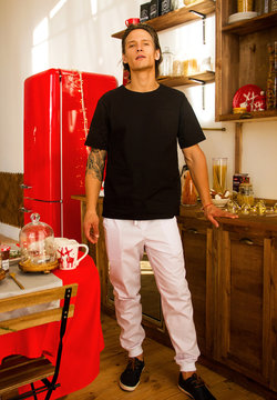  Nurse Man In Stylish Suit Is Standing And Looking Straight With Flirt With One Hand Near Wood Table On The Wooden Kitchen Background With Red Fridge , Medical Doctor Concept