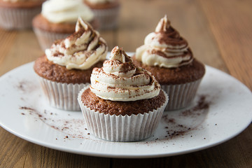Chocolate cupcakes with whipped cream on rustic wooden table. Homemade dessert. - obrazy, fototapety, plakaty