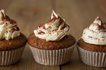 Chocolate cupcakes with whipped cream on rustic wooden table. Homemade dessert.