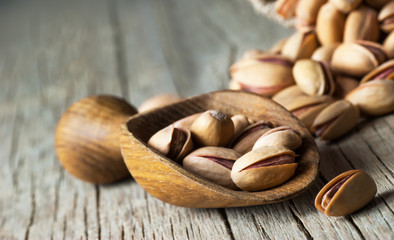 Pistachio in nutshell on wooden rustic backdrop in wooden shovel, composition of pistachios great for healthy and dietary nutrition. Concept of nuts
